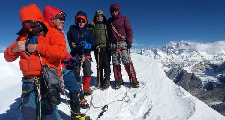 Groep klimmers gekleed voor koud weer op een besneeuwde bergtop.