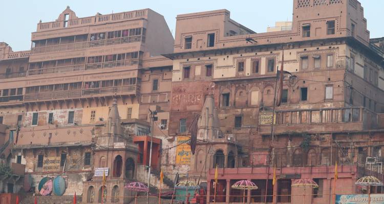 Weathered historic buildings and temples lining the ghats of Varanasi in soft morning haze.