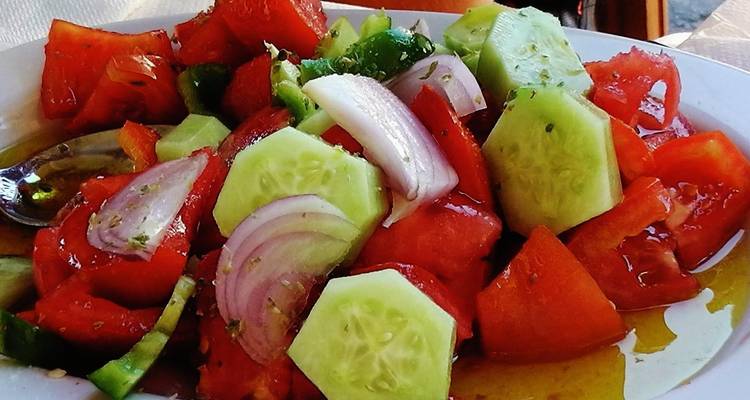 Nahaufnahme eines frischen griechischen Salats mit Tomaten, Gurke und Zwiebeln.