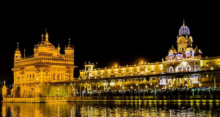 Golden temple at night, reflecting in the water.