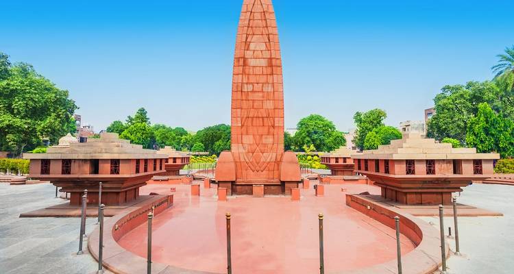 Red stone memorial monument surrounded by greenery.