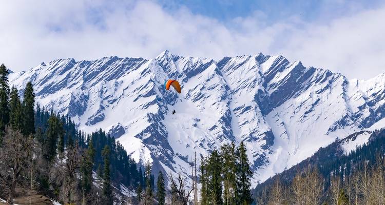 Mountain landscape with a paraglider in the sky.