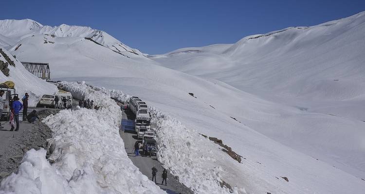 Snow-covered mountain pass with vehicles and people