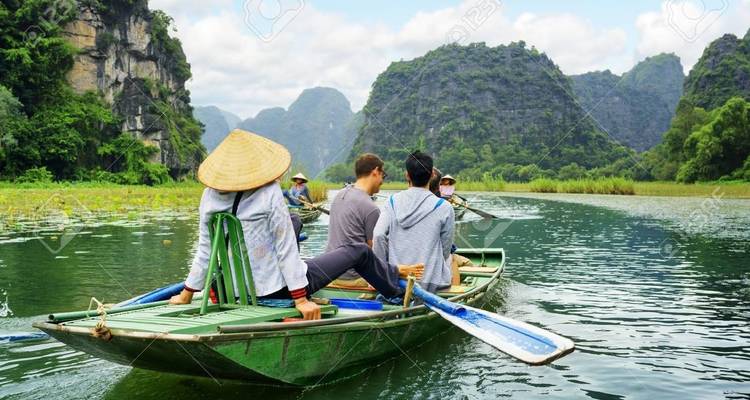Boat with people on a river surrounded by karst mountains.