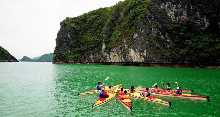 People kayaking near rocky cliffs in the water.