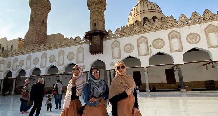 Gruppe von Frauen in traditioneller Kleidung, die vor einer Moschee stehen.