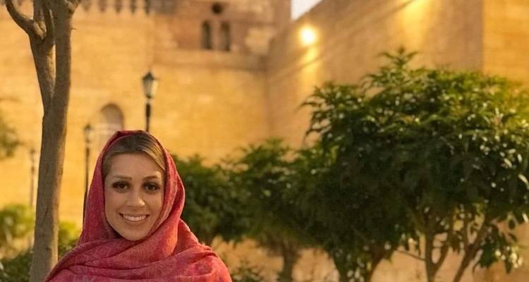 Eine Frau in traditioneller Kleidung vor historischen Gebäudemauern.