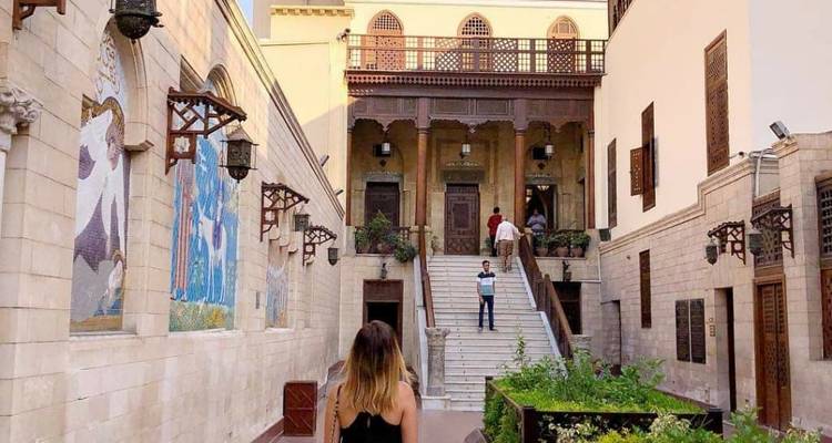 Eine Person, die auf ein historisches Gebäude mit einer Treppe zugeht.