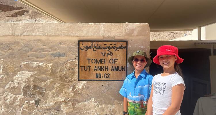 Dos niños están parados al lado de un letrero del Monumento de Tutankamón en el Valle de los Reyes.