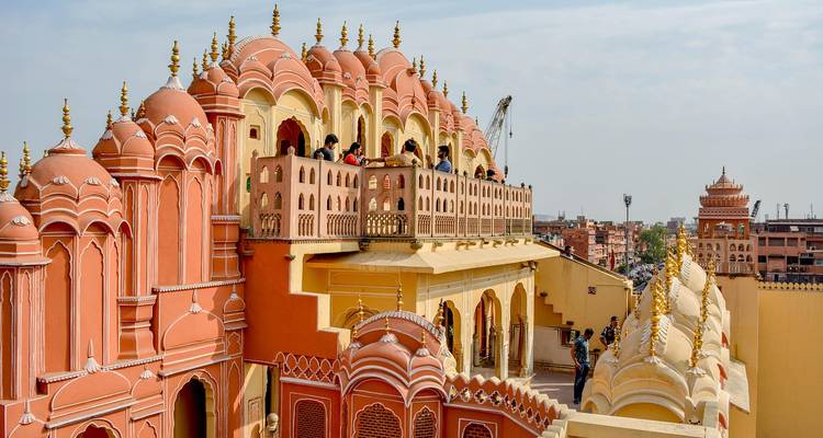 Visitors admire the ornate pink façade and latticed windows of Jaipur's Hawa Mahal from above.