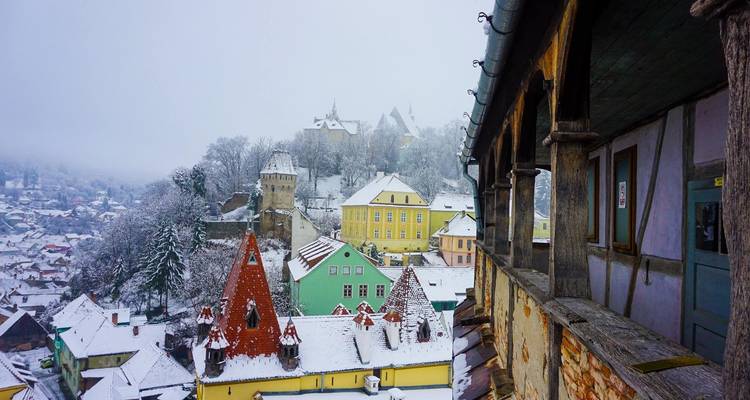 Vue d'une ville colorée et enneigée depuis un balcon.