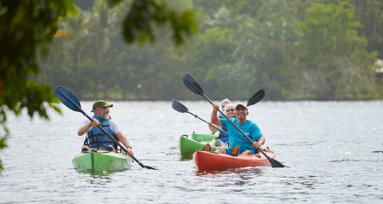 Deux kayaks colorés avec des pagayeurs souriants éclaboussent sur un lac calme.