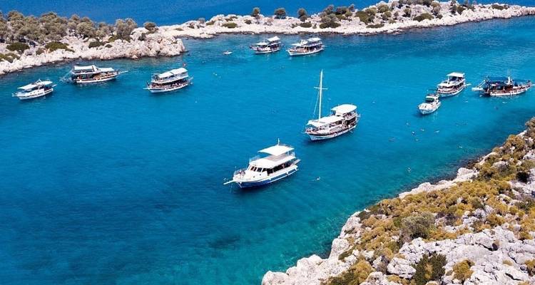 Barcos en aguas azul cristalinas rodeados de costas rocosas.