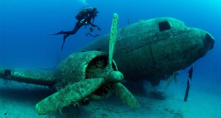 Buzo explorando un avión hundido bajo el agua.