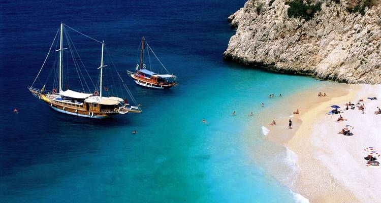 Barcos anclados cerca de una playa rocosa.