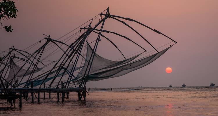 Silhouette of Chinese fishing nets at sunset over calm waters.