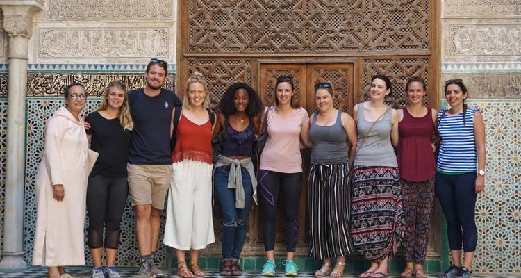Groupe de personnes devant une porte en bois finement sculptée.