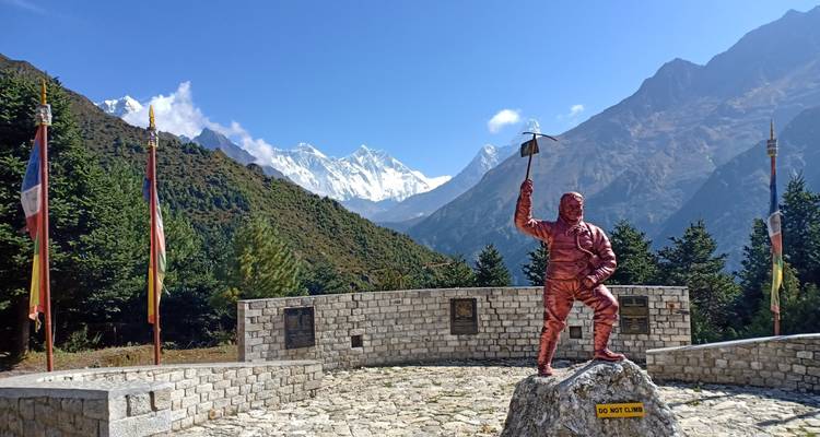 Statue d'un grimpeur avec des montagnes en arrière-plan.