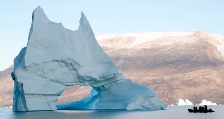 Gran iceberg en una región fría del Ártico con un pequeño bote cerca.