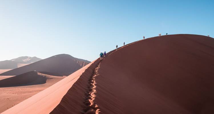 Uitgestrektheid van rode zandduinen onder een levendige blauwe hemel.