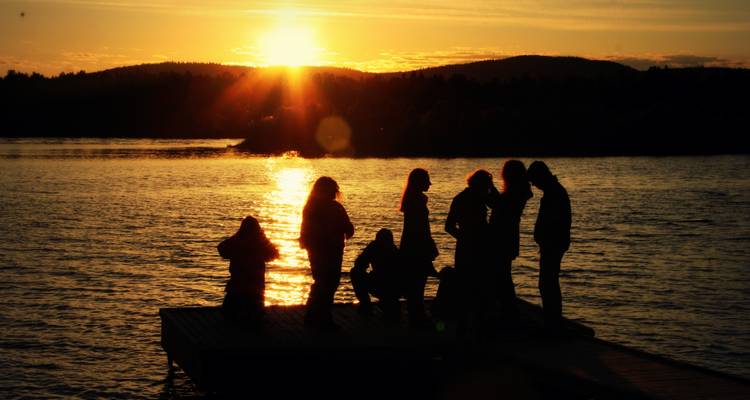Siluetas de personas en un muelle durante el atardecer.