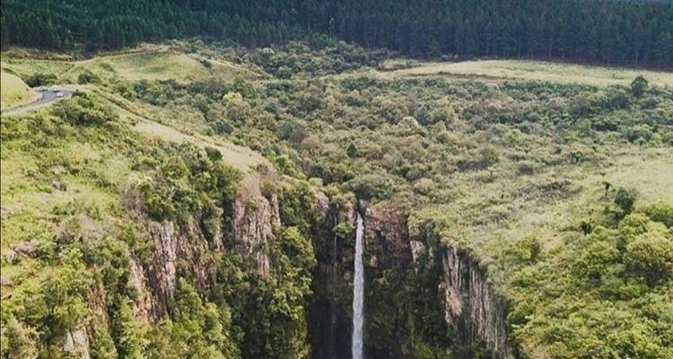 Vue aérienne d'une cascade entourée d'une végétation luxuriante et de falaises.