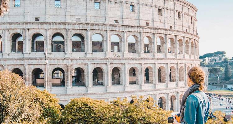 Traveler gazing at the iconic Colosseum with camera in hand on a sunny day
