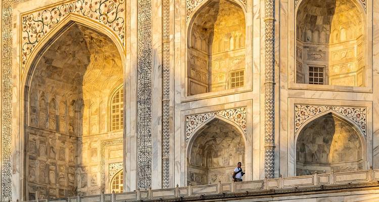 Ornately carved facade of the Taj Mahal at sunset.