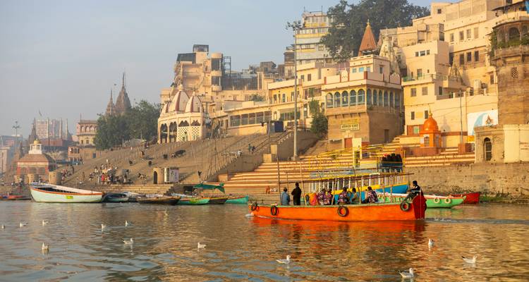 Colorful riverside scene in Varanasi with boats and buildings.