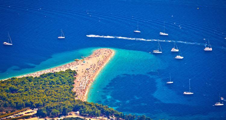 Vue aérienne de la langue de sable de Zlatni Rat s'avançant dans les eaux bleu profond de la mer Adriatique parsemées de voiliers.