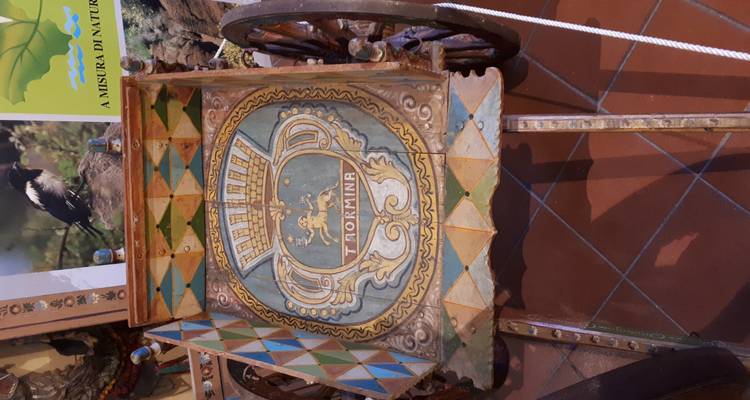 Bemalter Wagen mit 'TAORMINA' darauf, umgeben von bunten Fliesen.