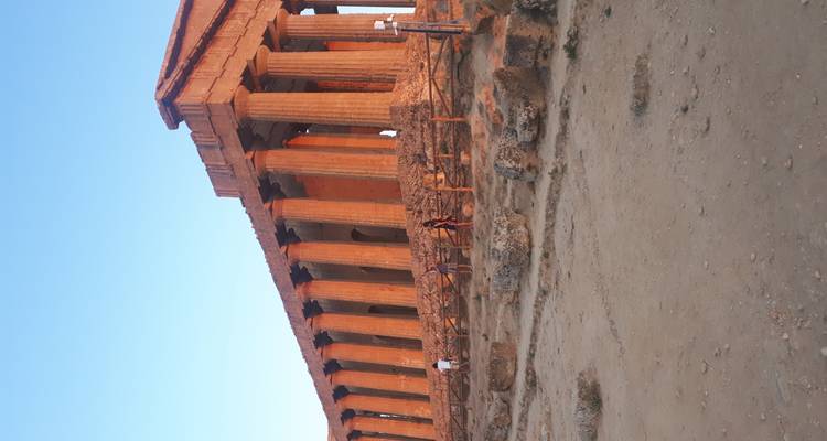 Menschen erkunden eine große Tempelruine in der Sonne.