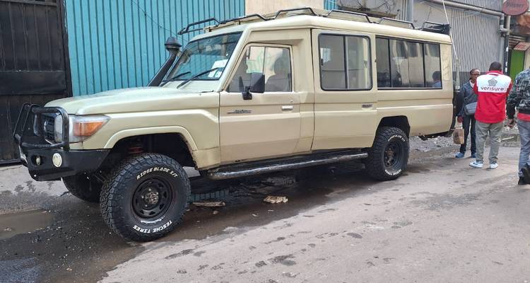 Parked safari vehicle in an urban street with a person nearby.