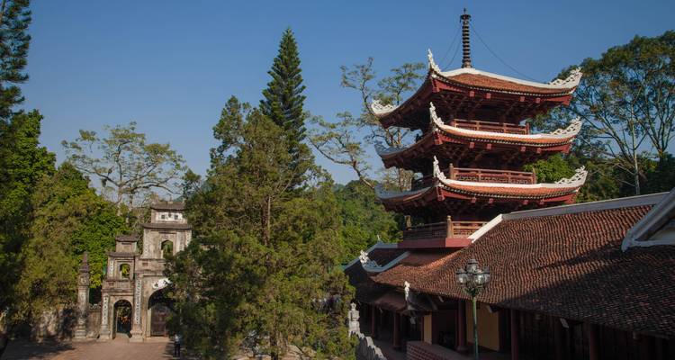 Pagode met rood dak omringd door groen onder een heldere blauwe hemel.