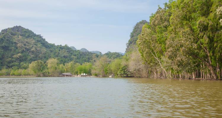 Een vredige rivier die stroomt tussen groene heuvels en bomen.