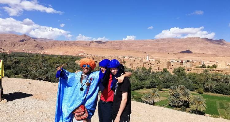 Menschen in traditioneller Kleidung mit einer Wüstenlandschaft im Hintergrund.