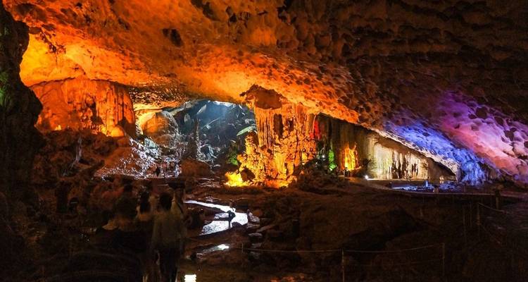 Cave interior with vibrant lighting and visitors.