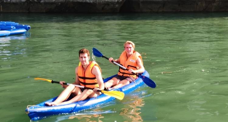 Deux personnes faisant du kayak avec des gilets de sauvetage sur une eau calme.