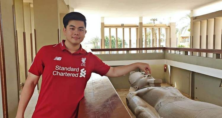 Mann berührt Statue einer liegenden Figur in einem Museum.