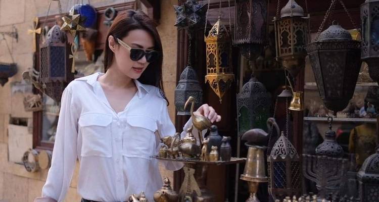 Frau beim Einkaufen auf einem Marktplatz mit traditionellen Laternen.