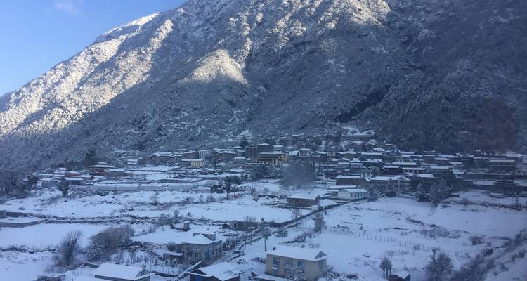 Schneebedecktes Dorf am Fuße einer Bergkette.