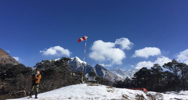 Person, die auf einem schneebedeckten Hügel steht, mit Bergen im Hintergrund.