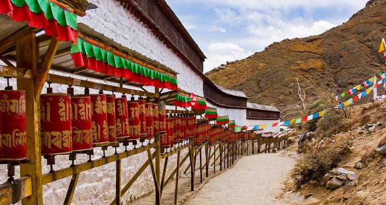 Bunte Gebetsmühlen, die entlang eines Weges aufgereiht sind.