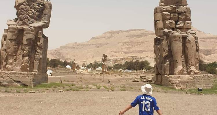 Junge in einem blauen Sporttrikot mit antiken Statuen im Hintergrund