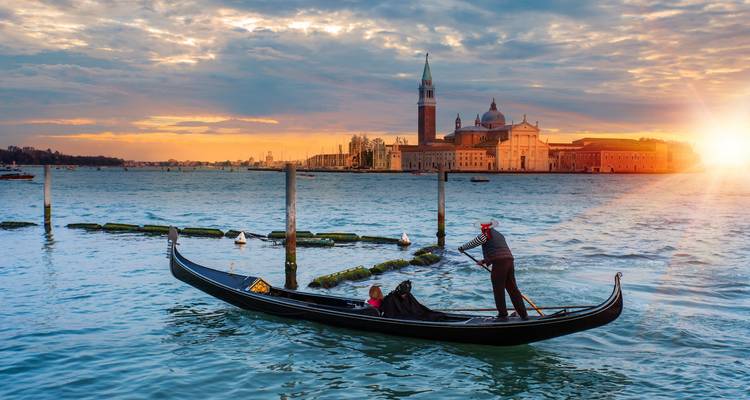 Gondola on a canal at sunset with a view of historic buildings