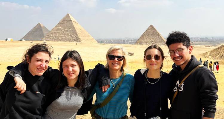 Groupe de personnes posant avec les pyramides en arrière-plan.