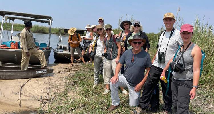 Groupe de voyageurs débarquant de bateaux à moteur et posant sur une rive sablonneuse du Delta de l'Okavango.