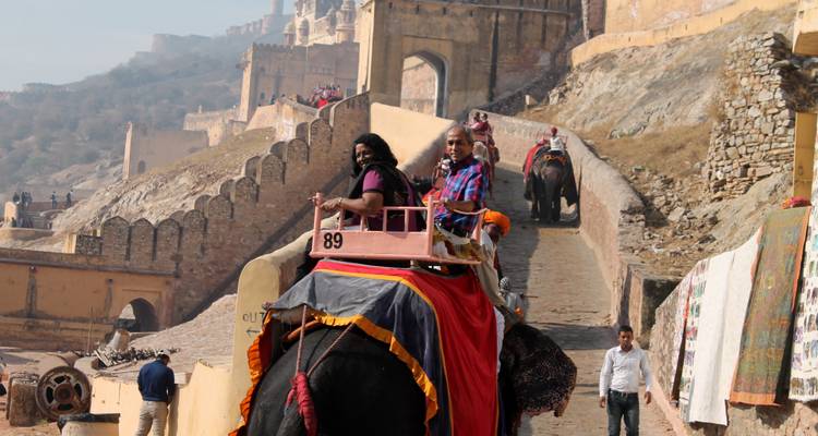 Tourists riding elephants on the path to a fort.