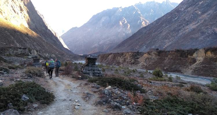 Wandelaars lopend in een brede vallei met rotsachtige bergen.