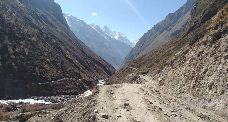 Onverharde weg die door een bergdal loopt onder een heldere hemel.